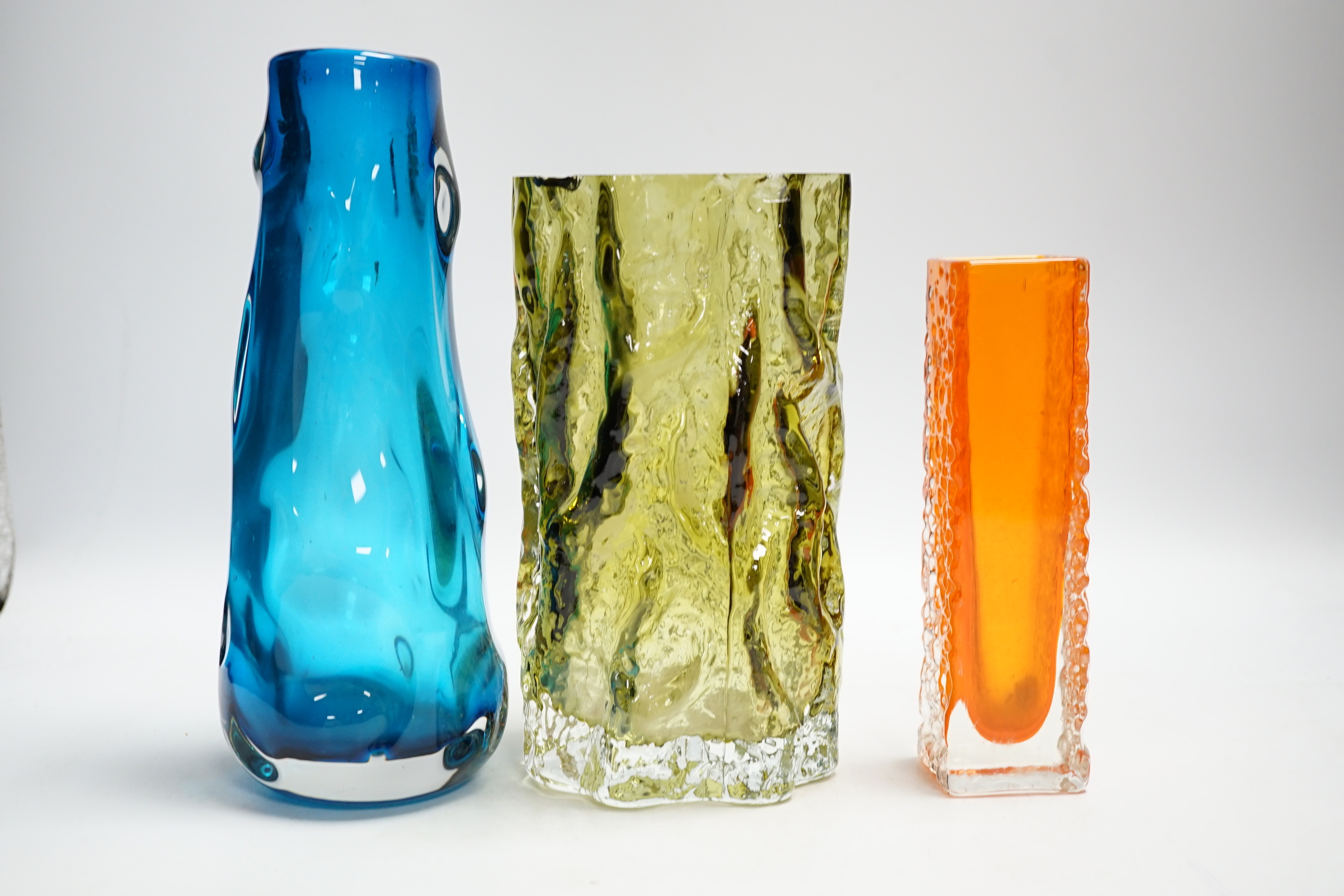 Three Whitefriars glass vases - a ‘Knobbly’ vase in kingfisher blue, a ‘Nailhead’ vase in tangerine and a ‘Bark’ vase in sage (cut down)